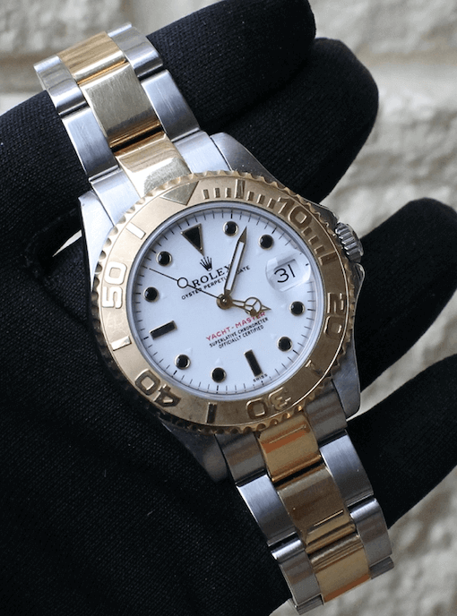 pre owned rolex watch held up Yachtmaster two tone white dial